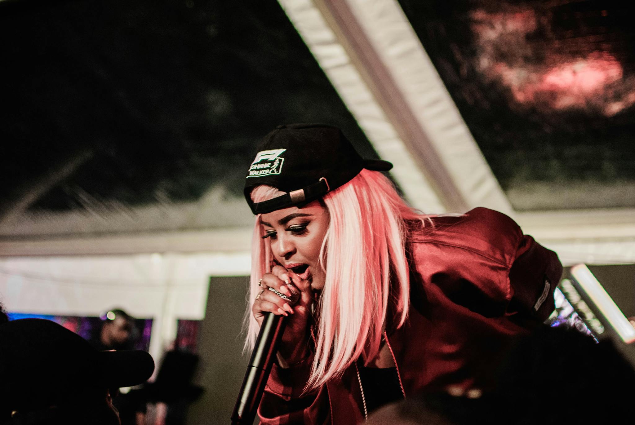 Vibrant live performance of a charismatic female rapper engaging with the audience.